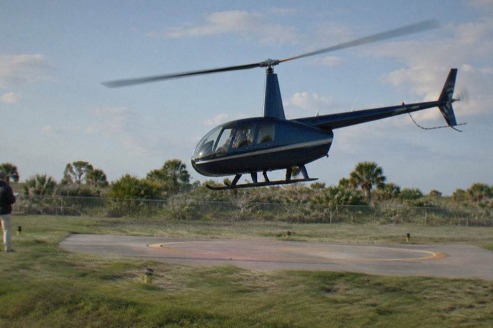 A sightseeing helicopter lifting off from a Kissimmee helipad near the theme park corridor