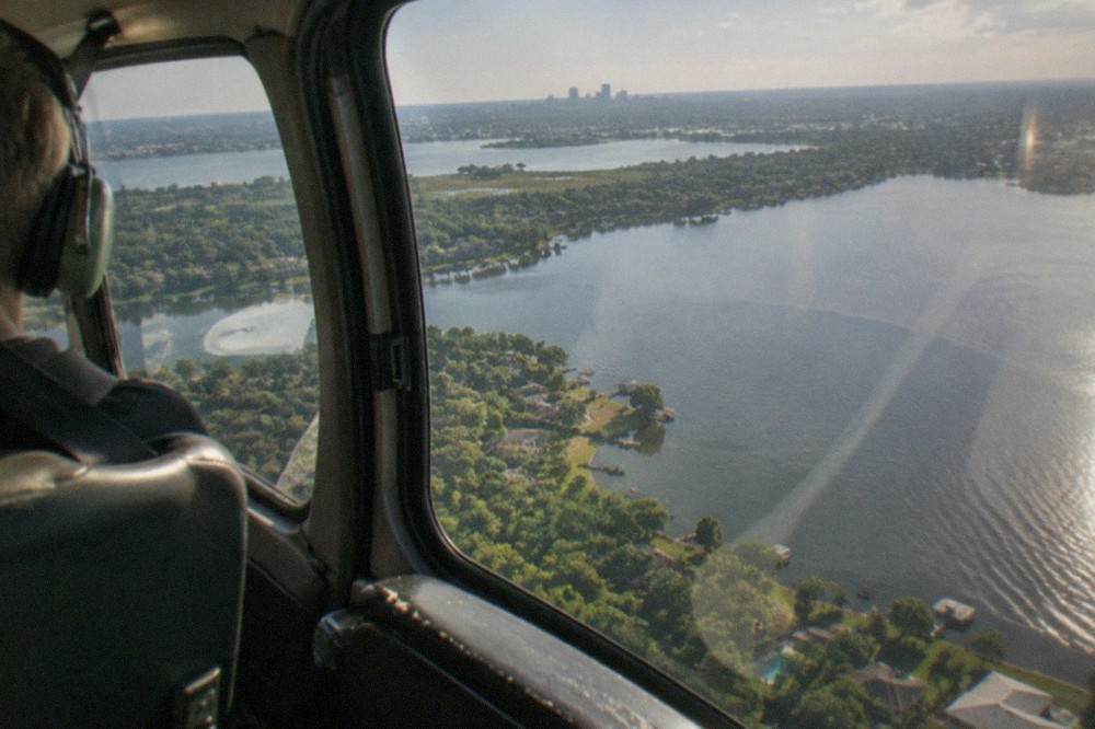 A helicopter cabin interior with large windows looking out over Florida water and treetops