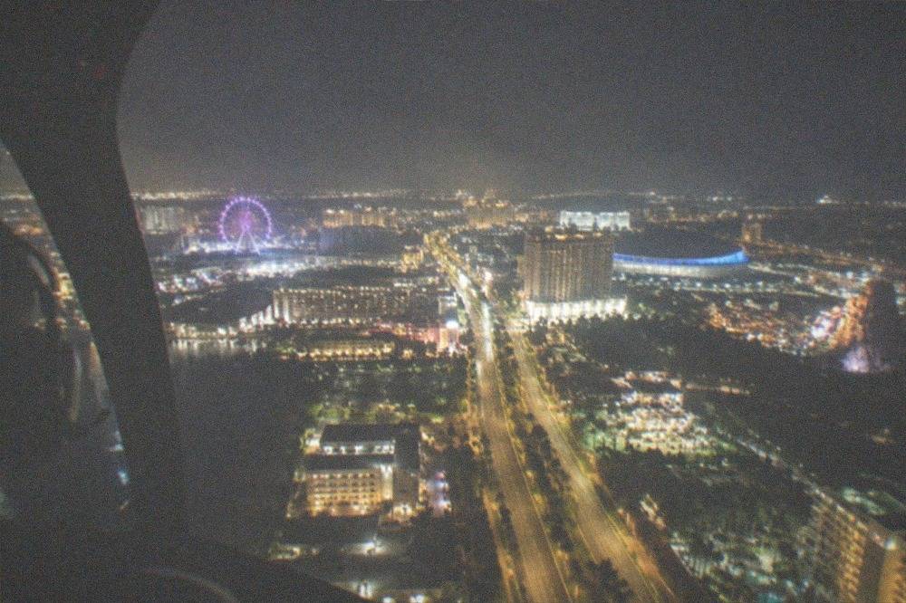Night aerial view of a lit-up Florida entertainment district with glowing streets and distant park lights