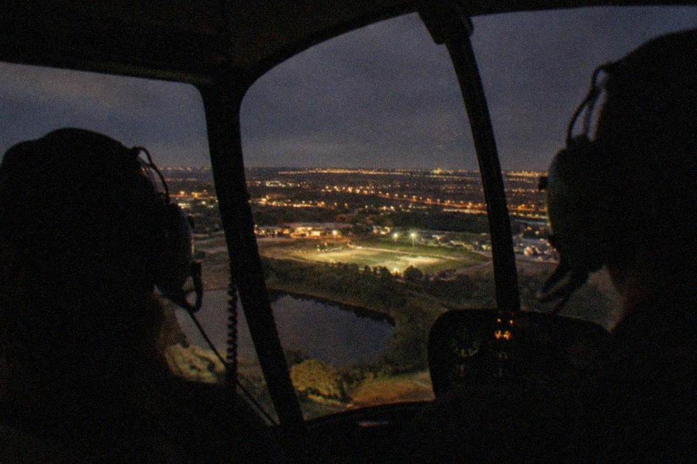 A helicopter cabin interior at night with city lights visible through the windows