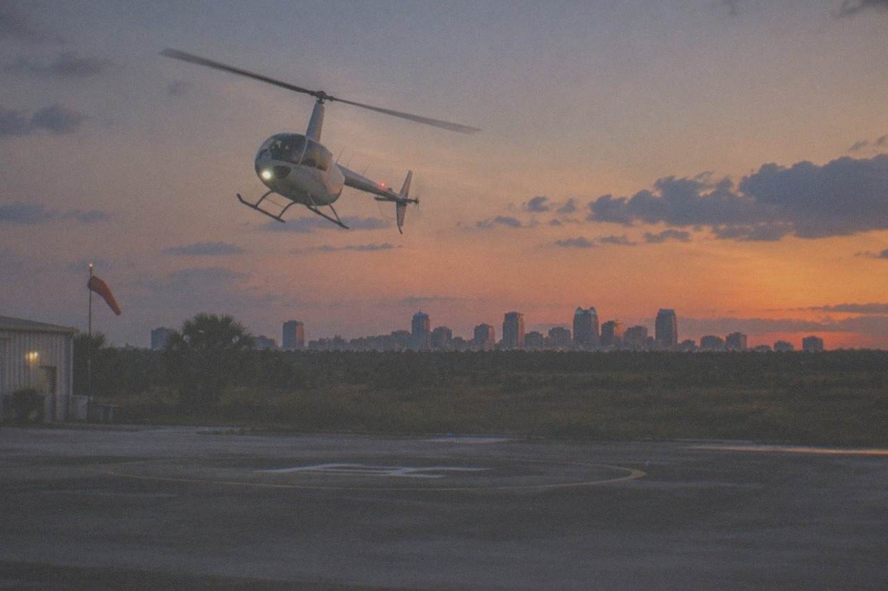 A helicopter flying over a lit-up Orlando skyline at dusk