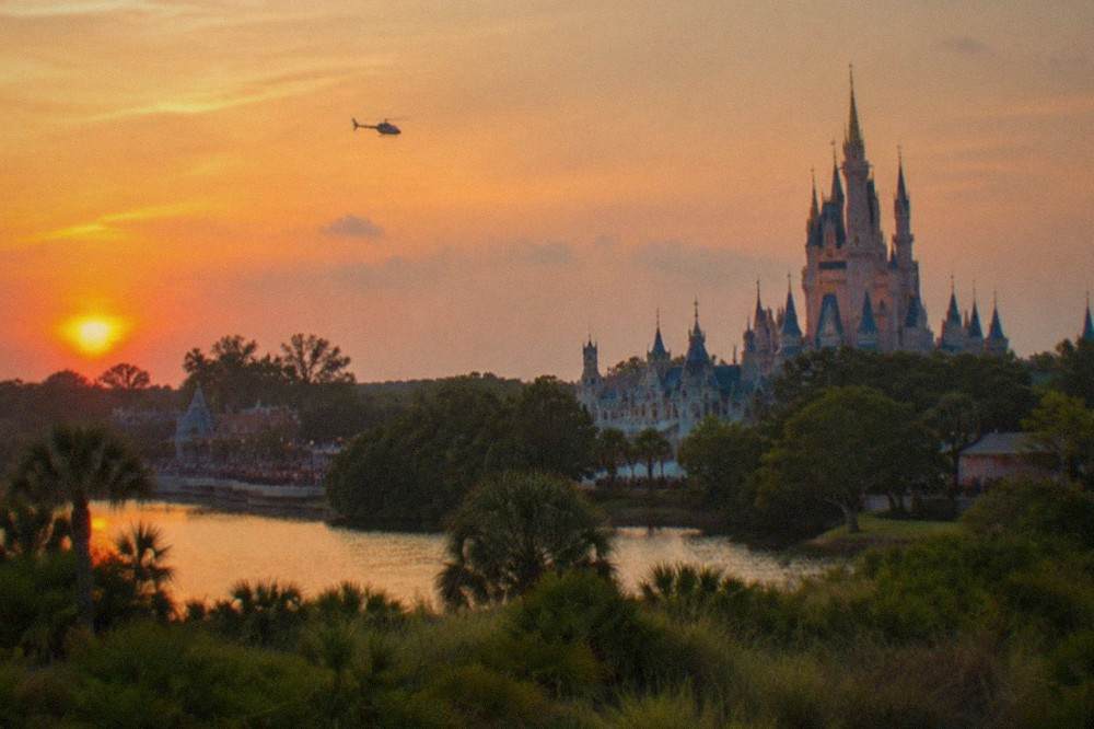A small helicopter flying above Florida lakes and resort towers in warm sunset light