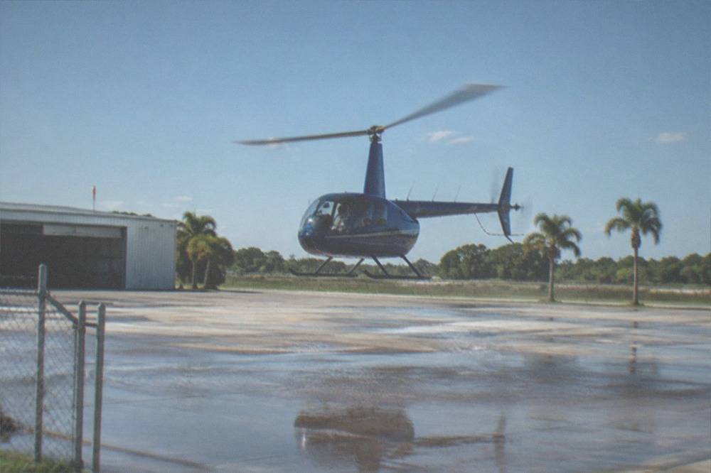 A helicopter lifting off from a Kissimmee helipad under a clear morning sky