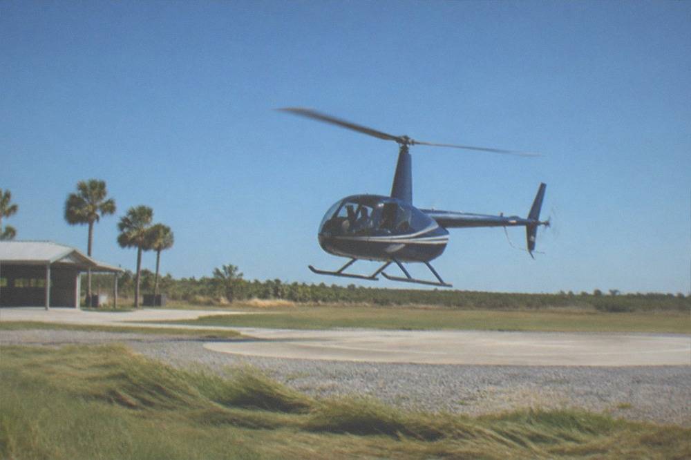 A helicopter lifting off a Kissimmee helipad under a clear morning sky