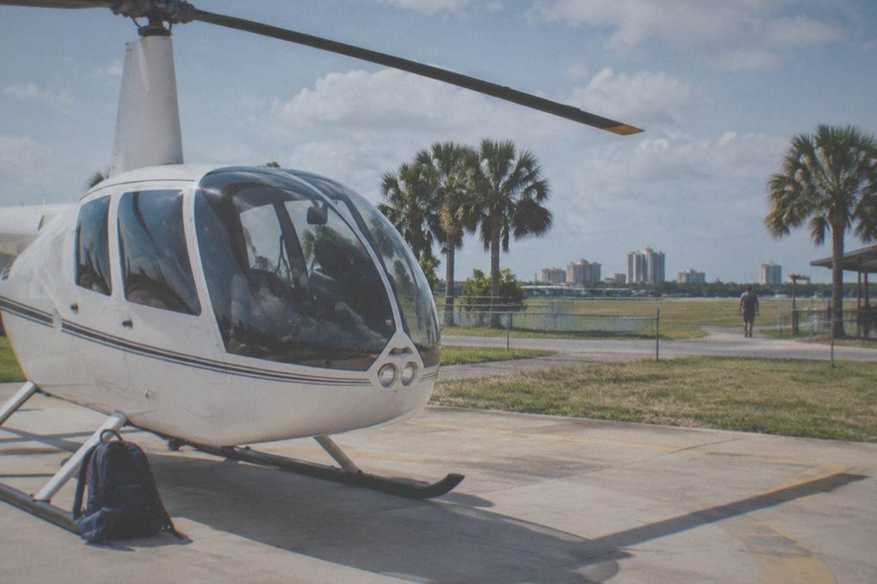 A small tour helicopter parked on a sunny Kissimmee helipad near theme park resorts