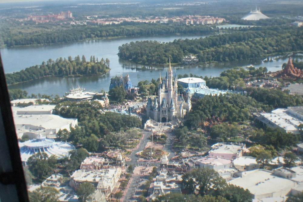 Aerial view of the Orlando theme park corridor with lakes and resort buildings under clear sky