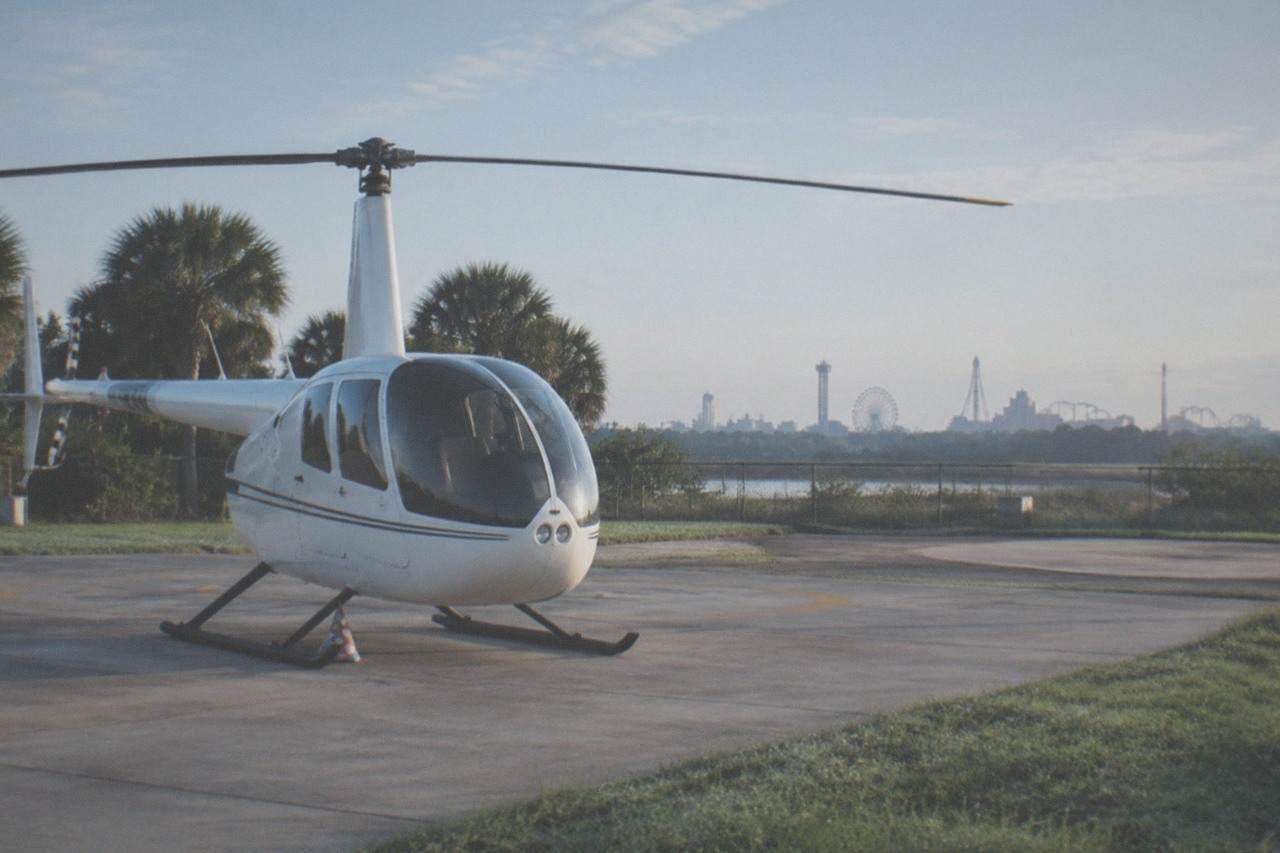 A small tour helicopter on a Kissimmee helipad with the Orlando theme park skyline in the distance
