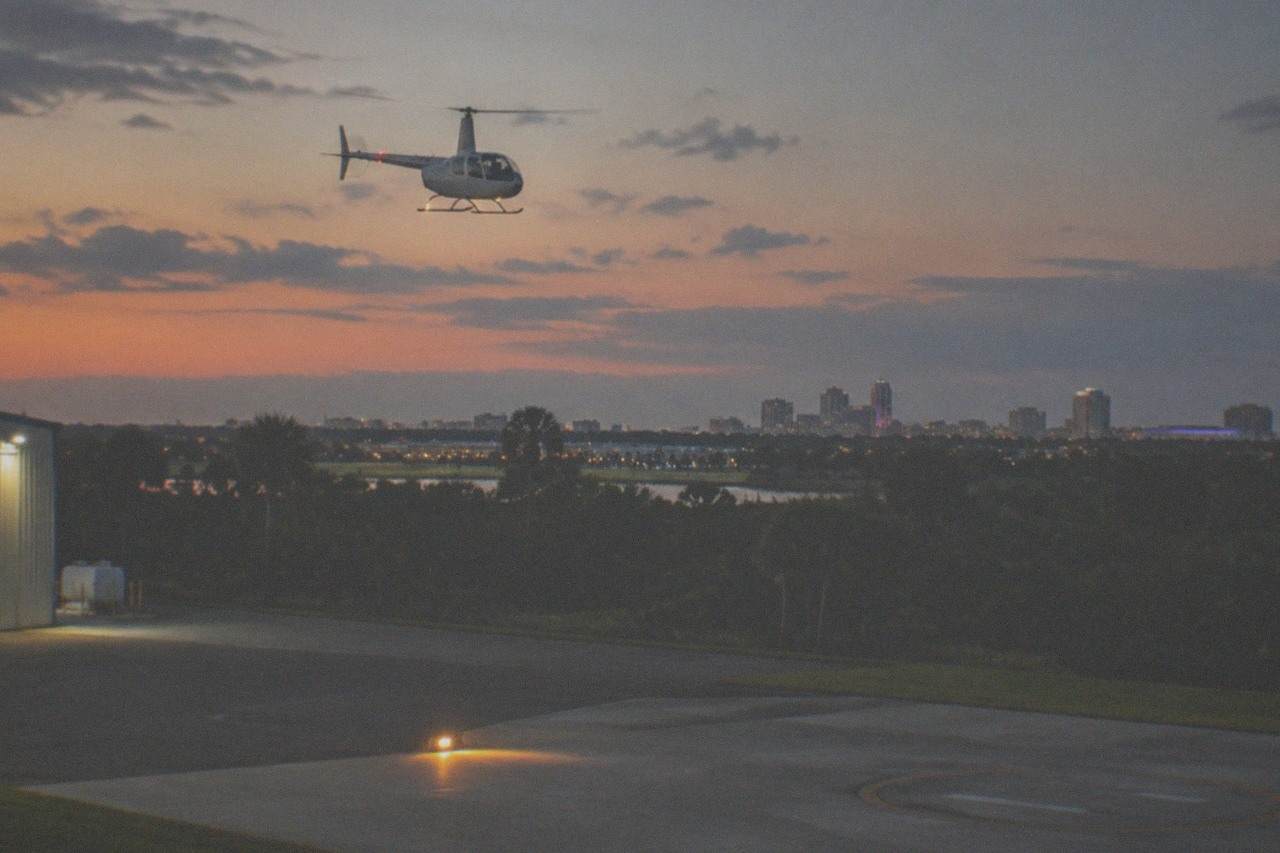 A helicopter in flight above Orlando at dusk with city lights beginning to glow below