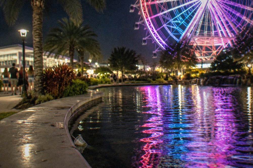 Ferris wheel and city lights reflecting over water in Orlando at night