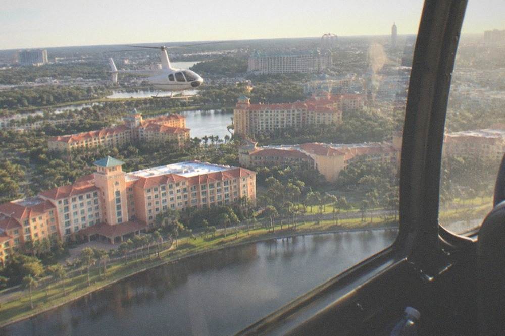 Helicopter flying over Florida lakes and resort corridor in late afternoon light