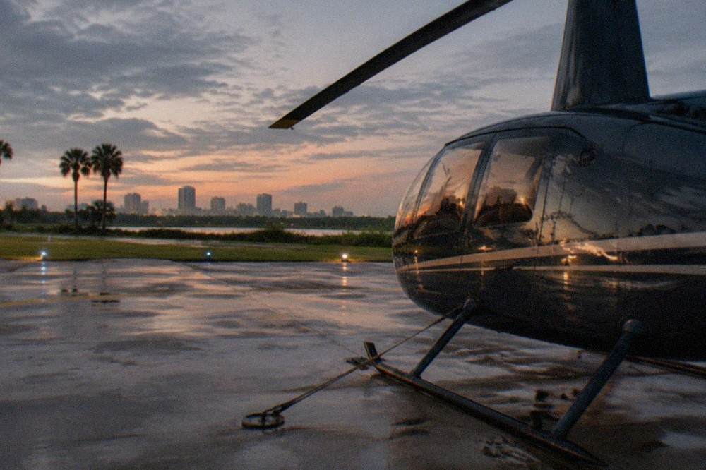 A private helicopter parked on a helipad at dusk with the Orlando skyline in the distance