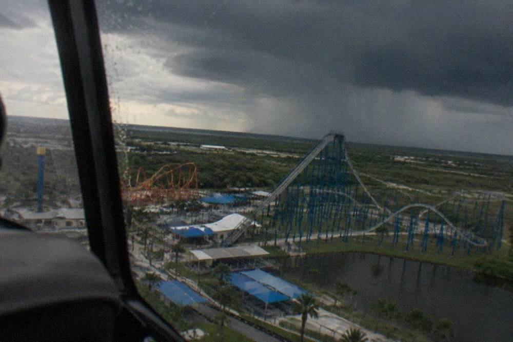 Dark storm clouds building over a flat Central Florida landscape with theme park structures in the distance