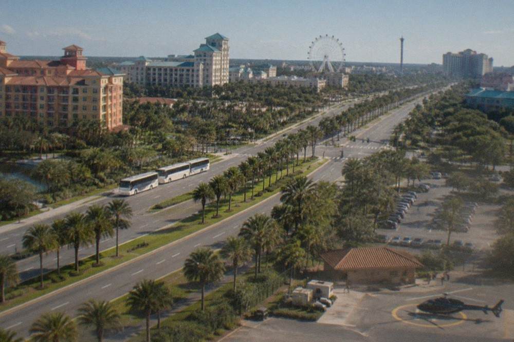 Aerial view of a wide Orlando resort boulevard lined with palm trees and hotels under a clear sky