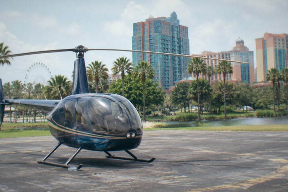 Small sightseeing helicopter on a paved pad with a resort skyline in the background