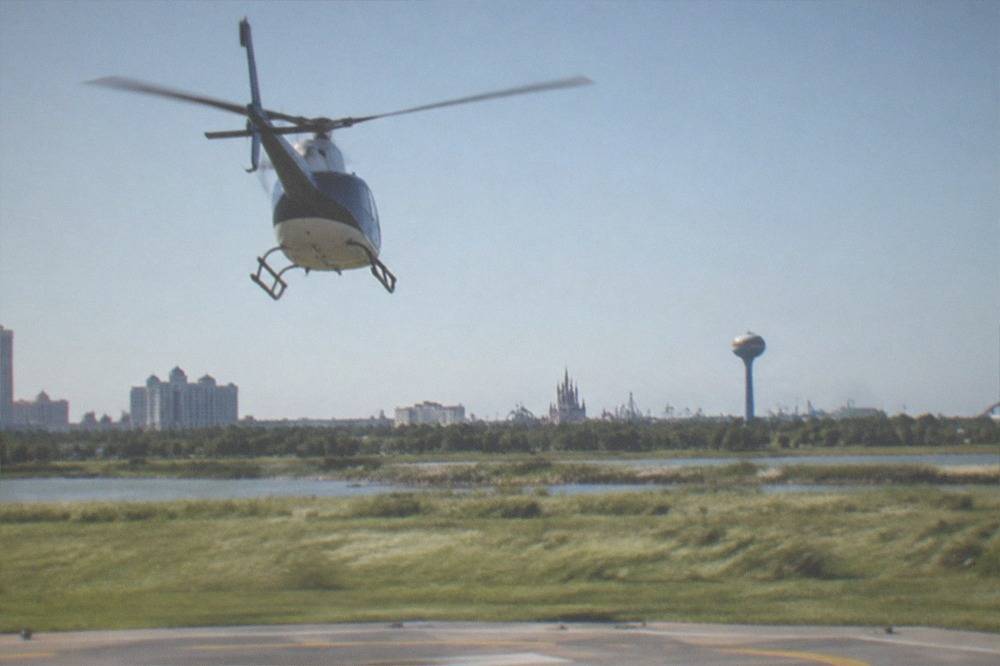 A sightseeing helicopter climbing away from a helipad into a clear blue sky over Central Florida