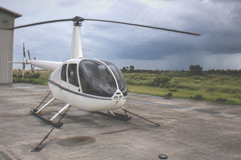 A helicopter on the ground under darkening summer storm clouds over the Kissimmee area