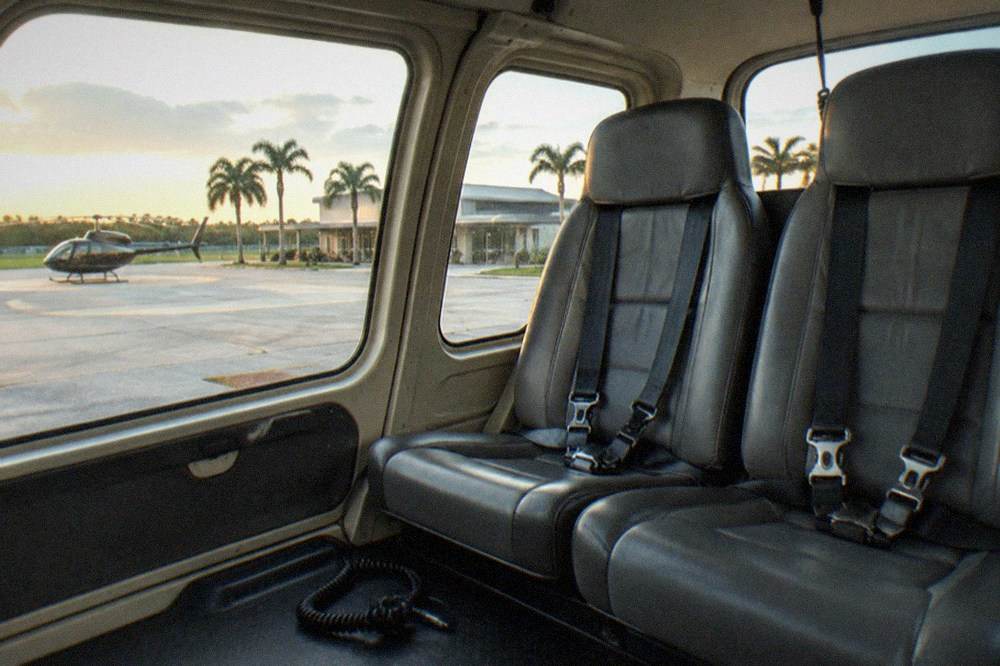 The interior of a small tour helicopter with three passenger seats and large side windows.