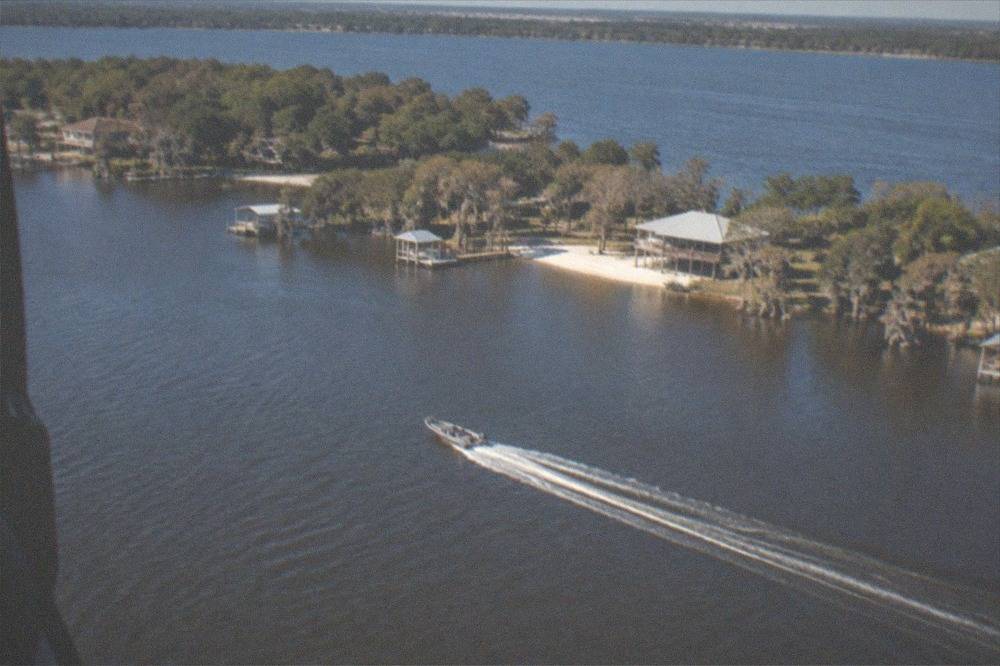 Aerial view of a Florida lake ringed by resort buildings and tree lines under a clear sky.