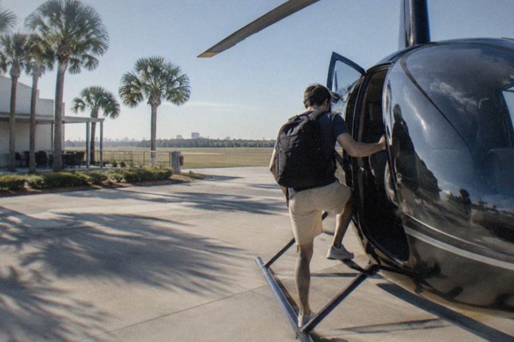 A passenger stepping onto a small tour helicopter on a clear Florida morning