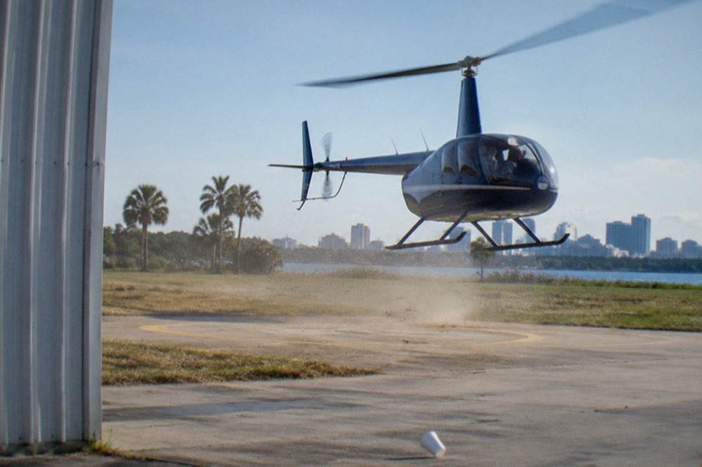 A sightseeing helicopter lifting off a Kissimmee helipad in morning light