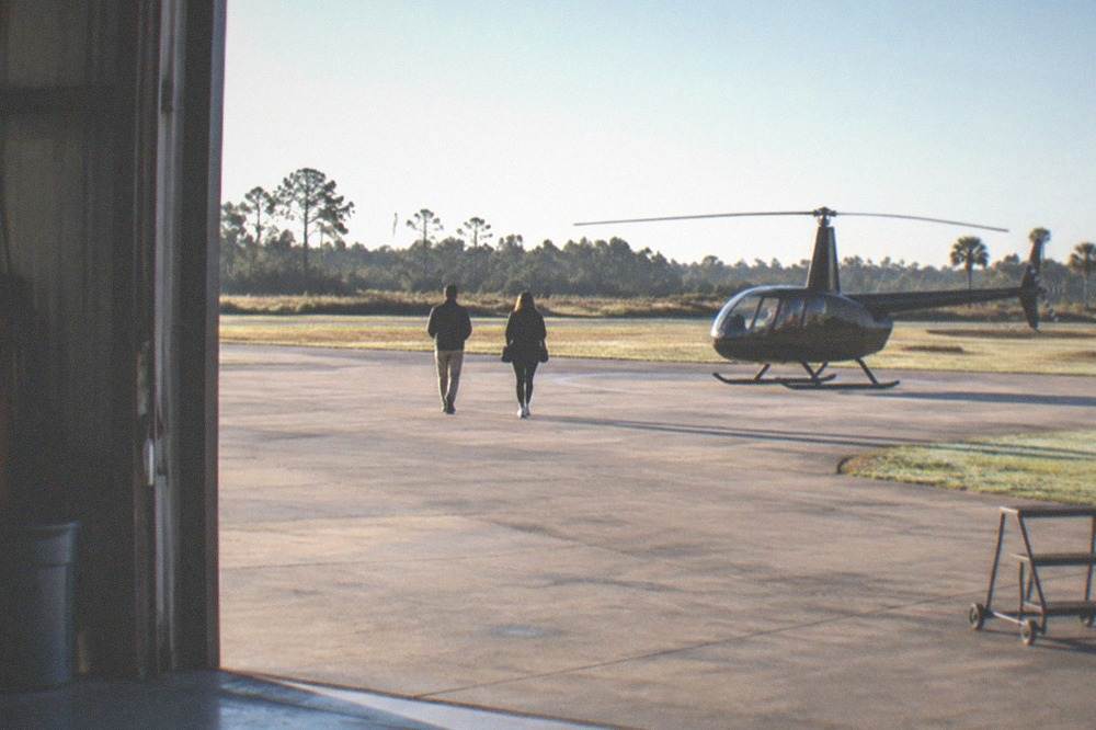 Passengers walking toward a waiting helicopter on a sunlit helipad
