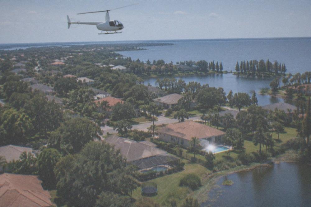 A tour helicopter in flight over Central Florida lakes and wooded suburbs near Kissimmee
