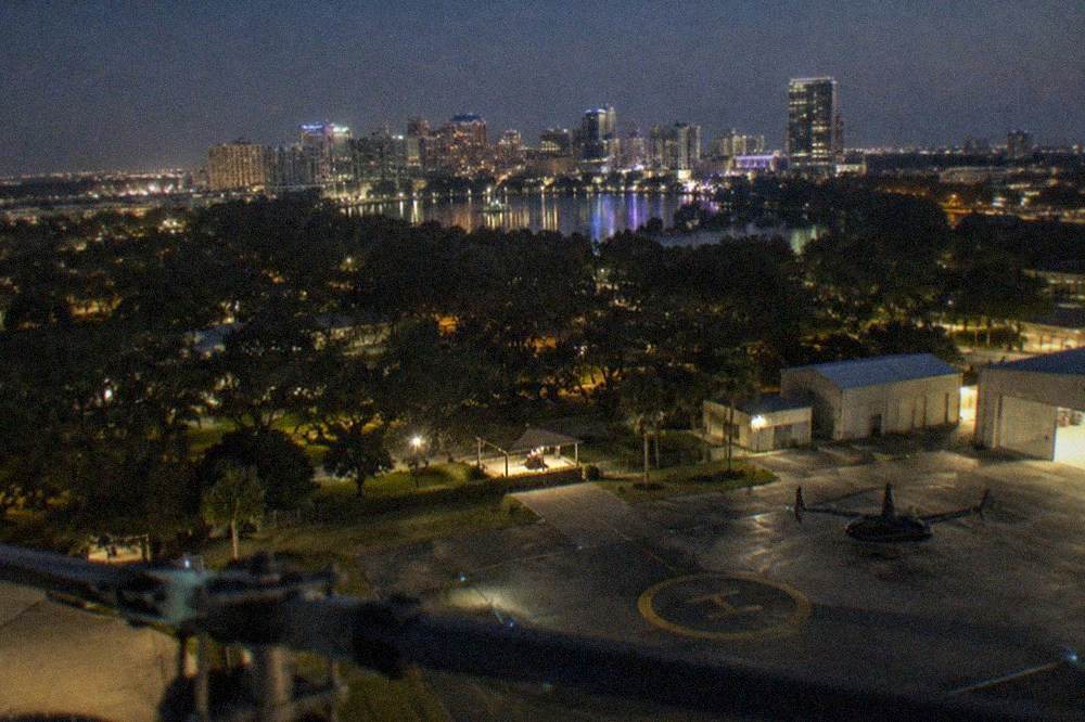 Night skyline of a Florida city with illuminated towers seen from a helicopter at altitude
