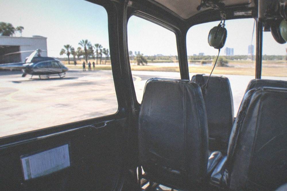 A helicopter cabin interior showing four worn passenger seats and large wraparound windows