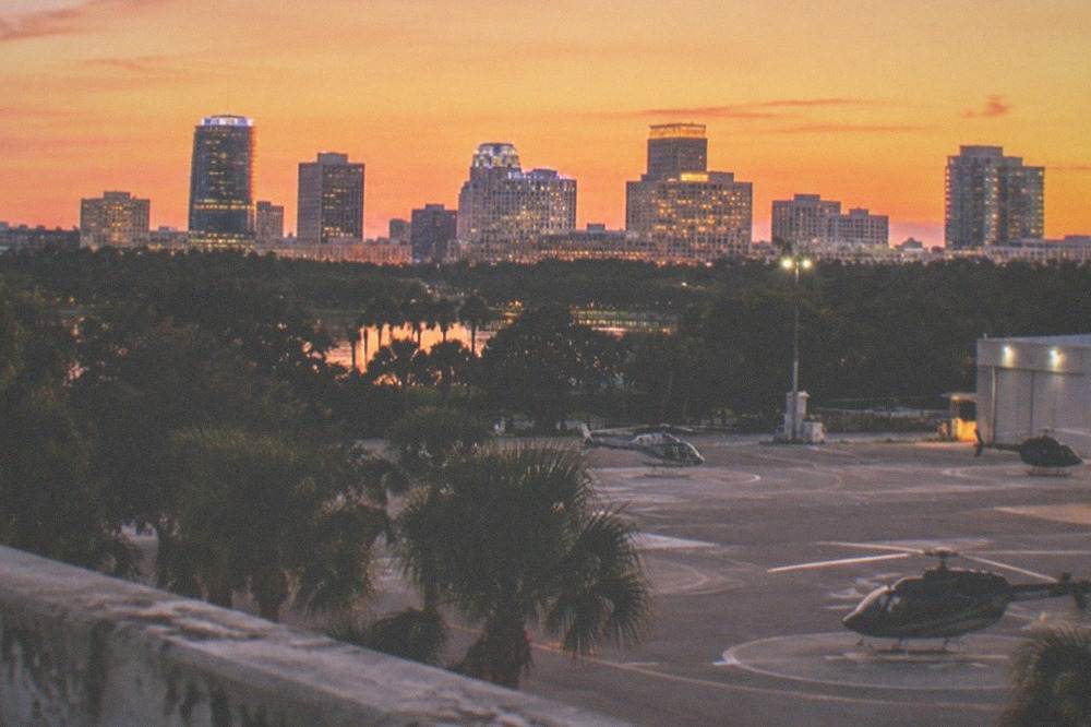 City skyline at dusk with buildings lit and a darkening orange sky