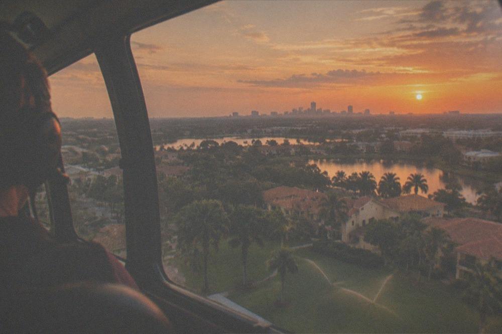 Sunset over a flat suburban corridor with distant towers and an orange horizon