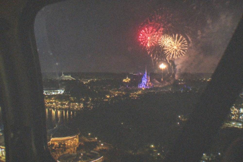 Fireworks bursting above a dark horizon as seen from inside a helicopter cabin window